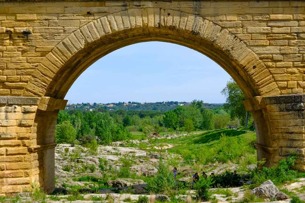 an arch in a stone wall with a view of a valley