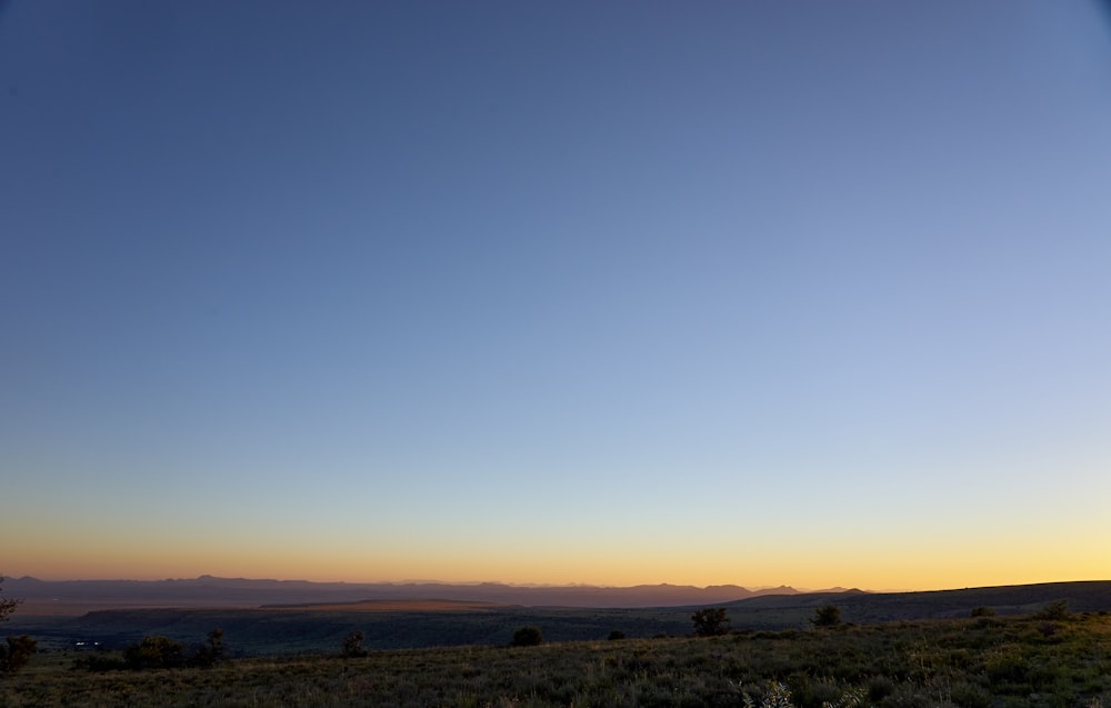 the sun is setting over the mountains in the distance