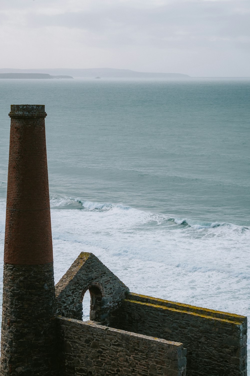 an old brick building near the ocean on a cloudy day