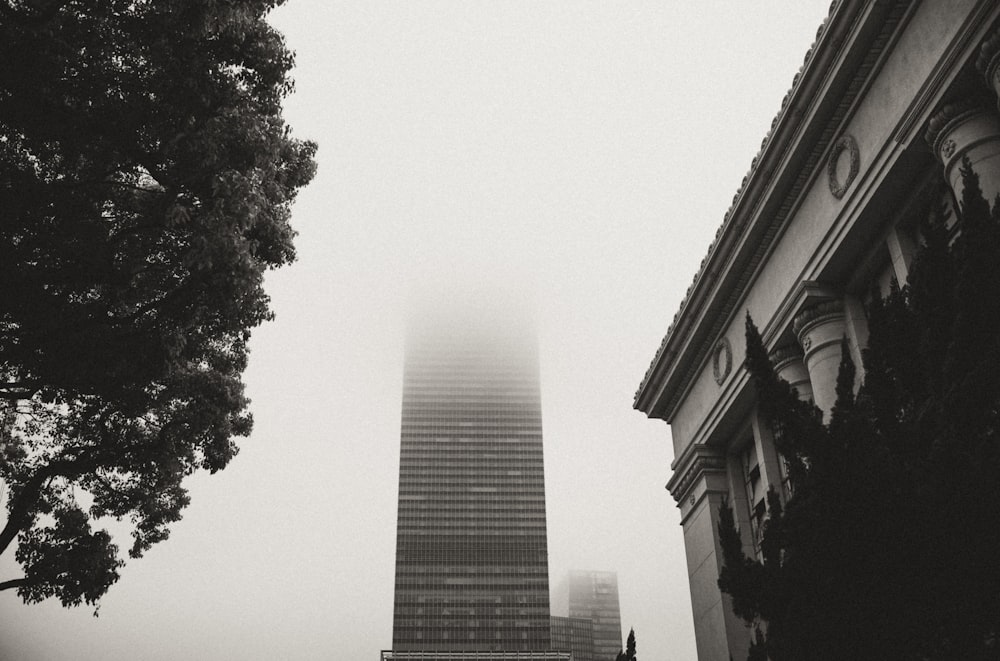 a very tall building towering over a city on a foggy day