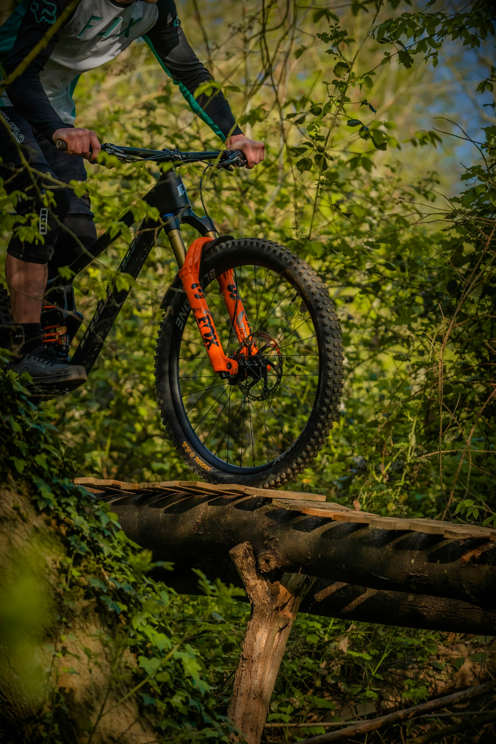 a man riding a bike over a wooden bridge