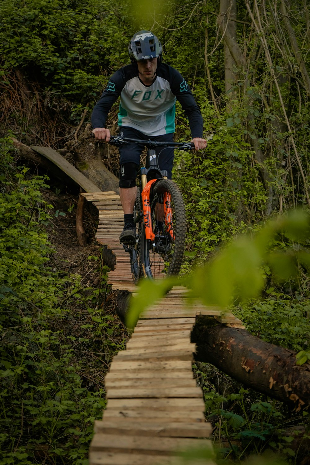 a man riding a bike across a wooden bridge