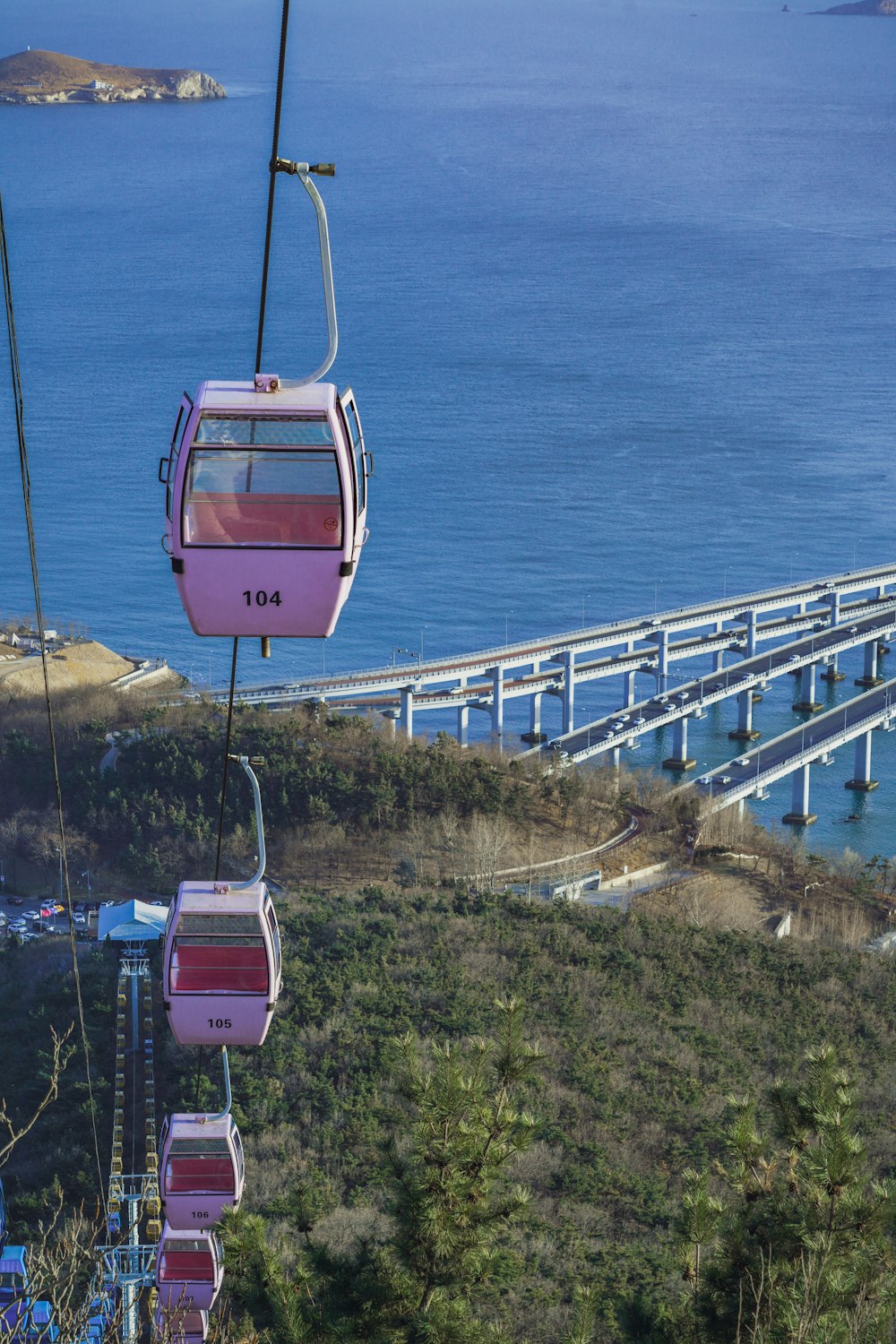 a pink trolly car going down a hill next to a bridge