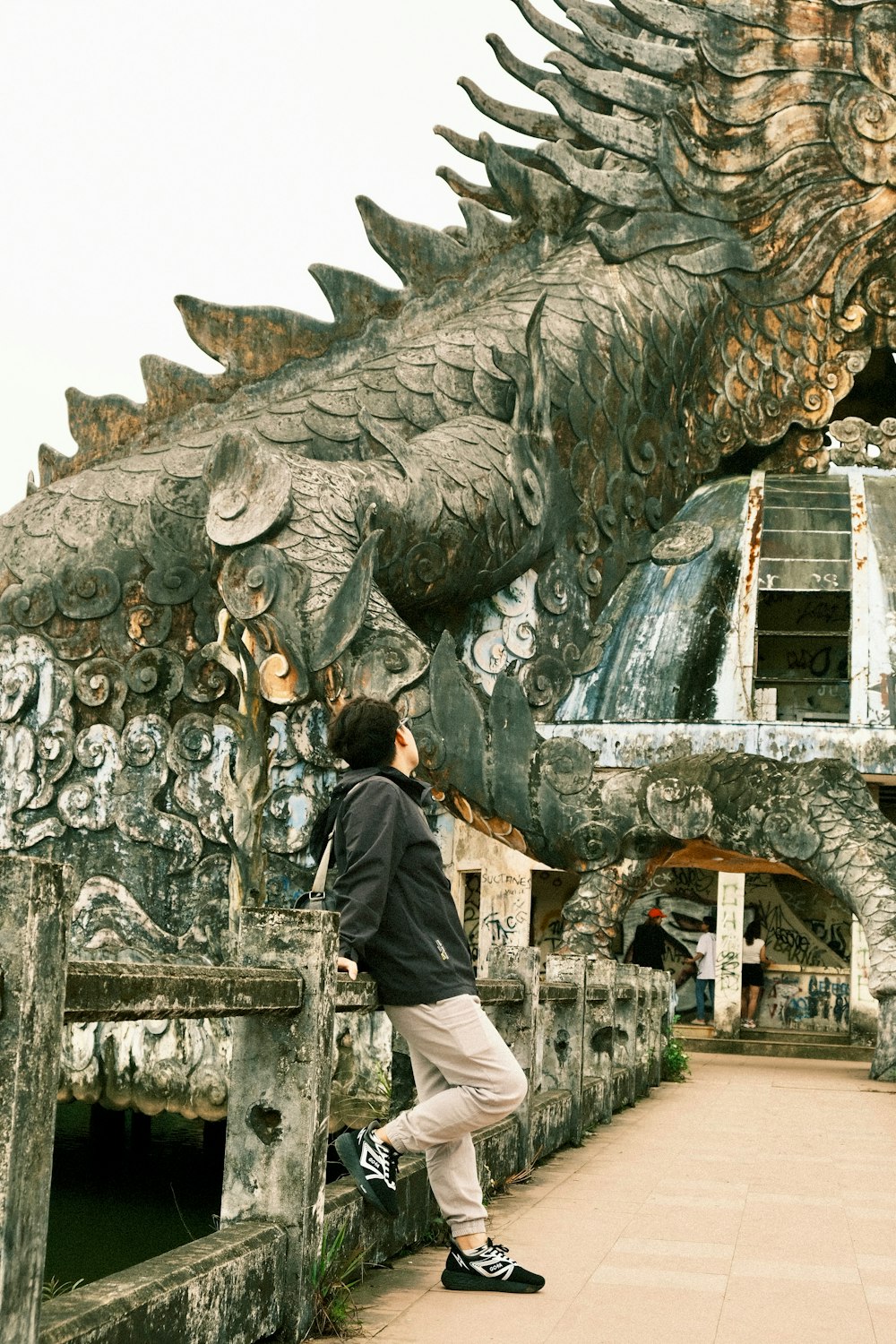 a man standing in front of a large dragon statue