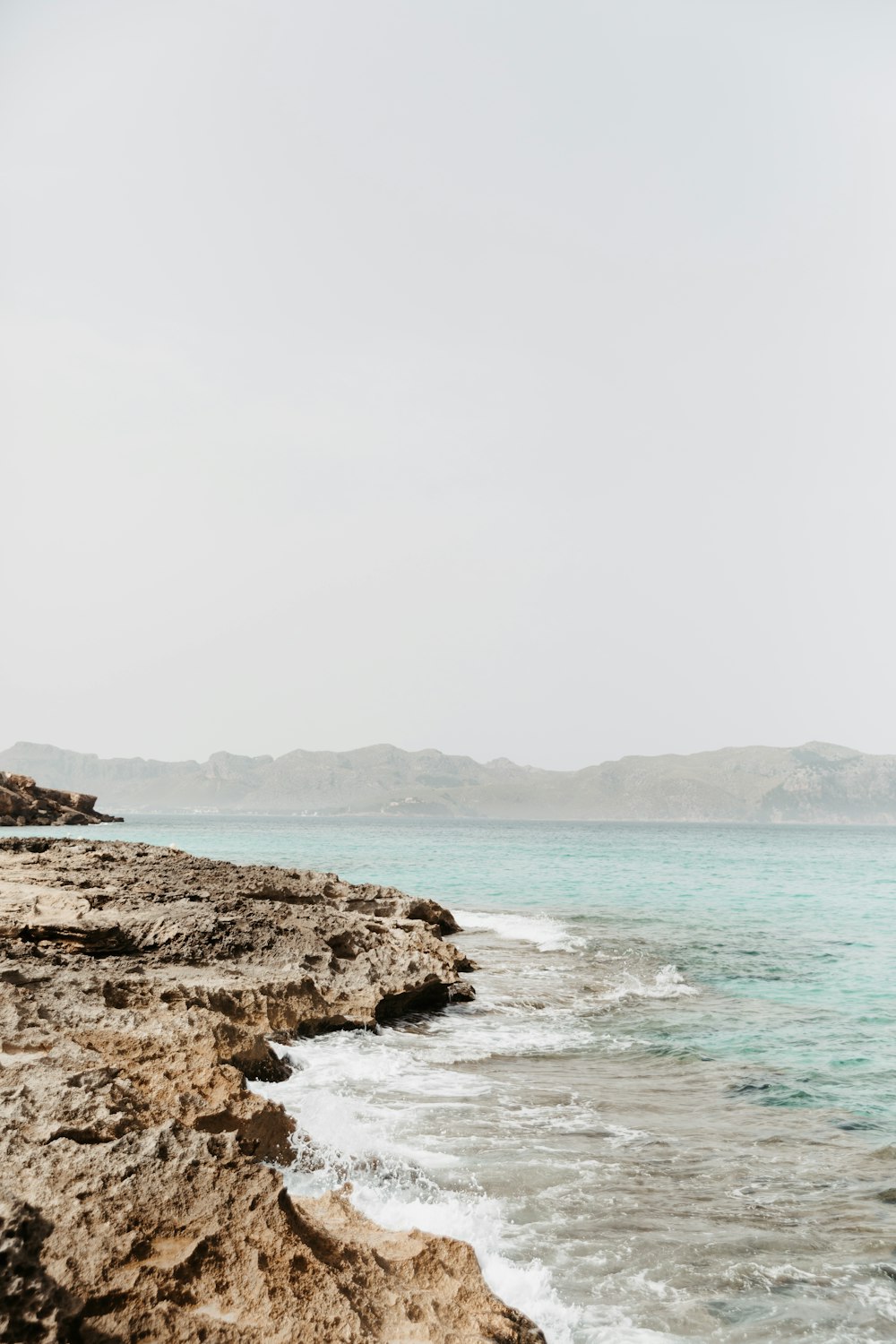 a person standing on the edge of a cliff near the ocean