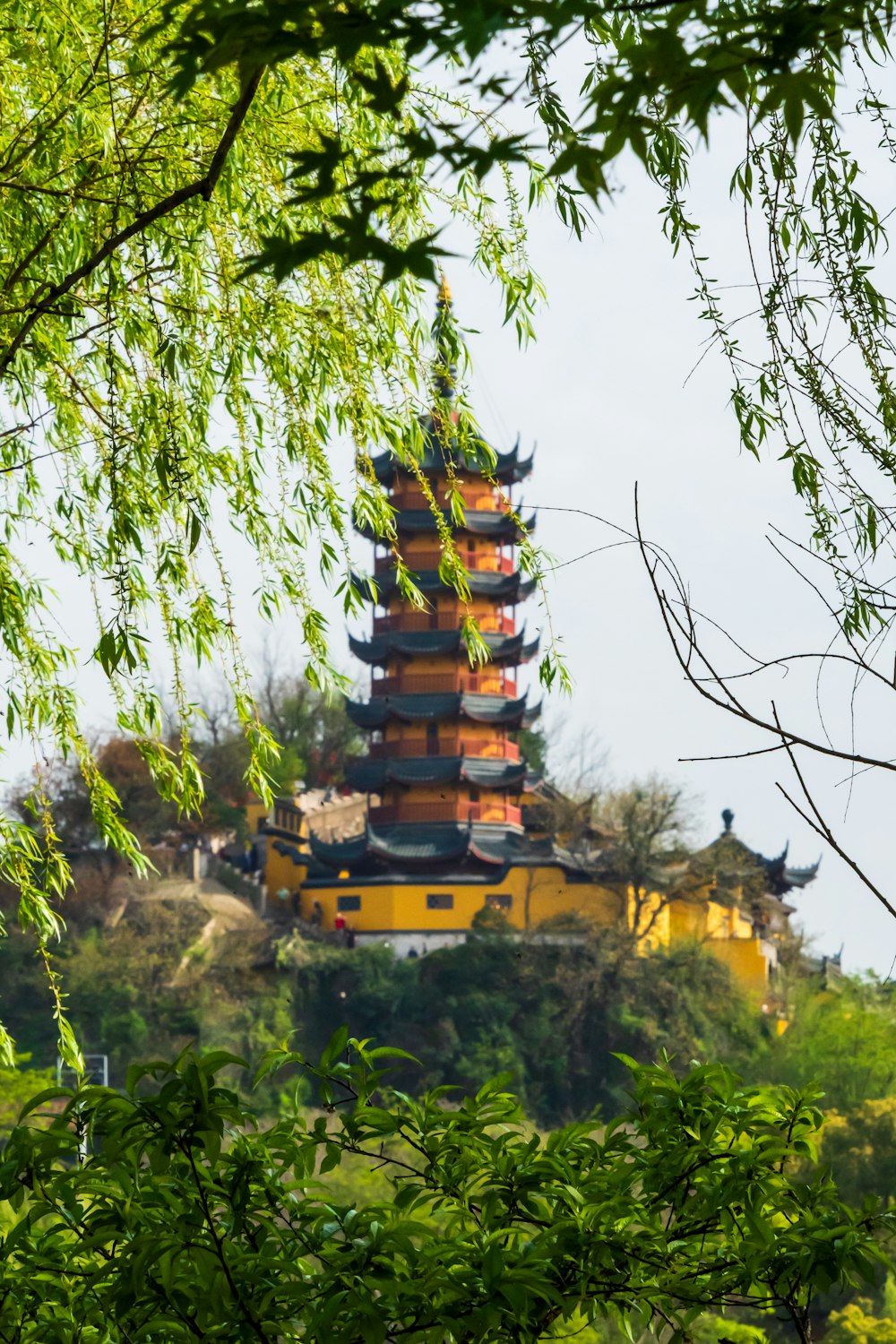 a tall yellow building sitting on top of a lush green hillside