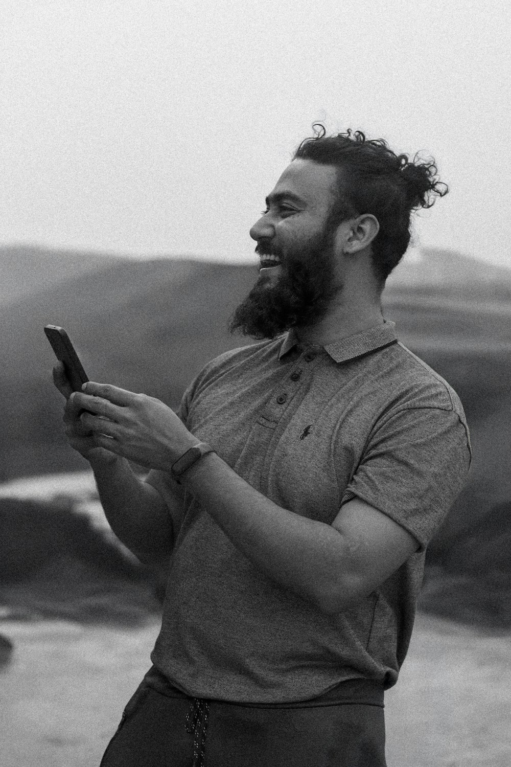 a man with a beard is looking at his cell phone