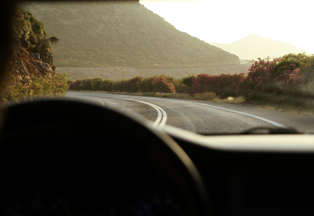 a view from inside a car of a road with mountains in the background