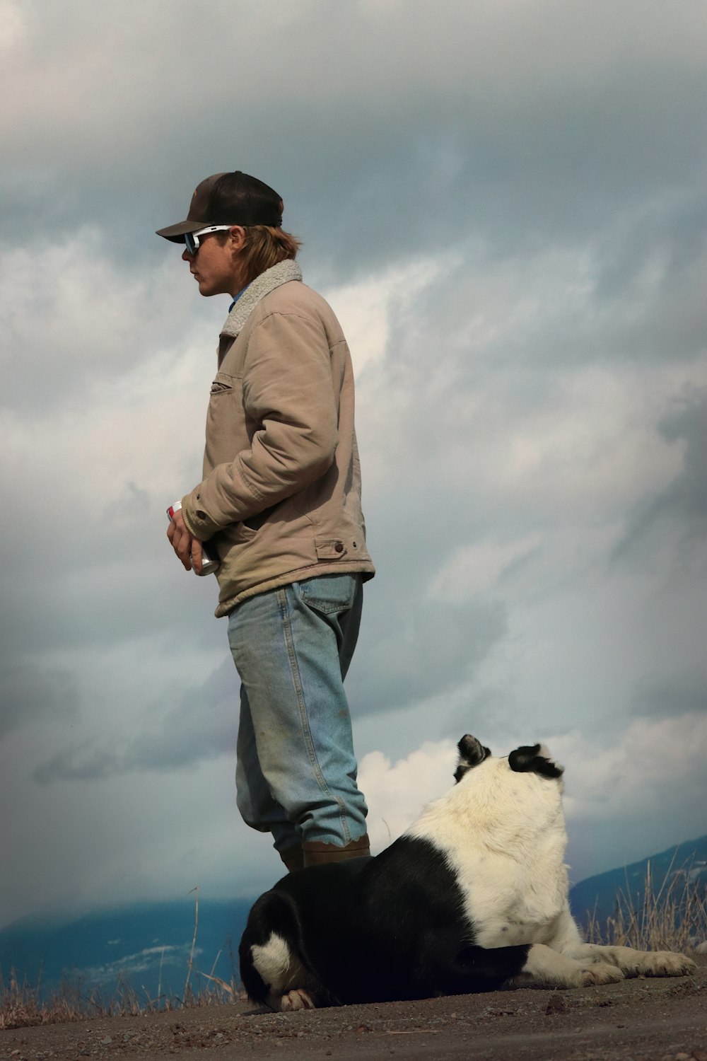 Un hombre de pie junto a un perro blanco y negro