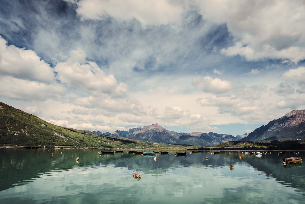 a body of water surrounded by mountains under a cloudy sky