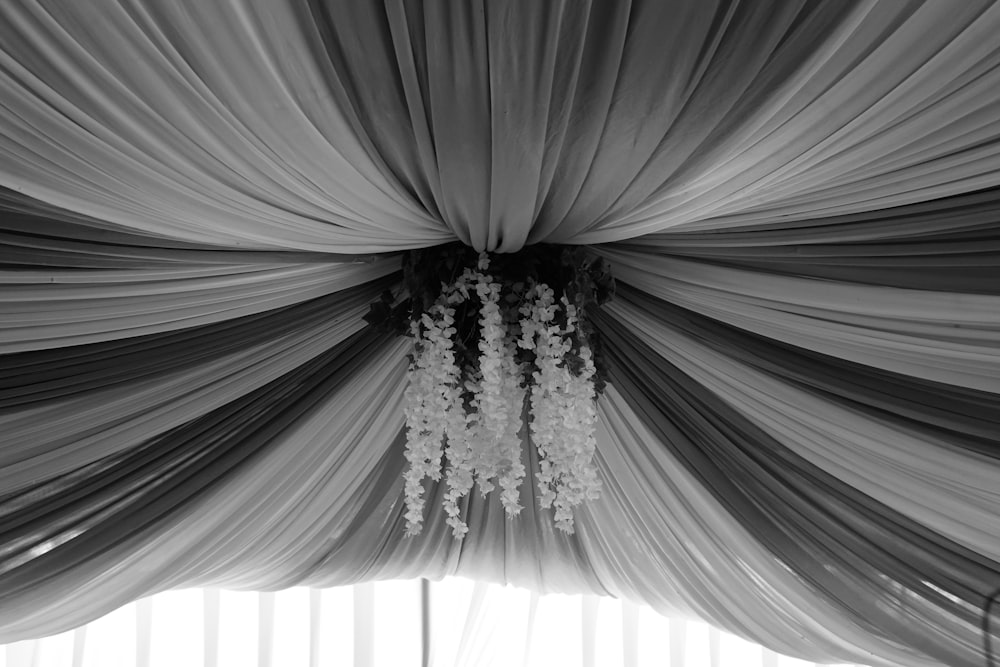 a black and white photo of a drape with flowers hanging from it