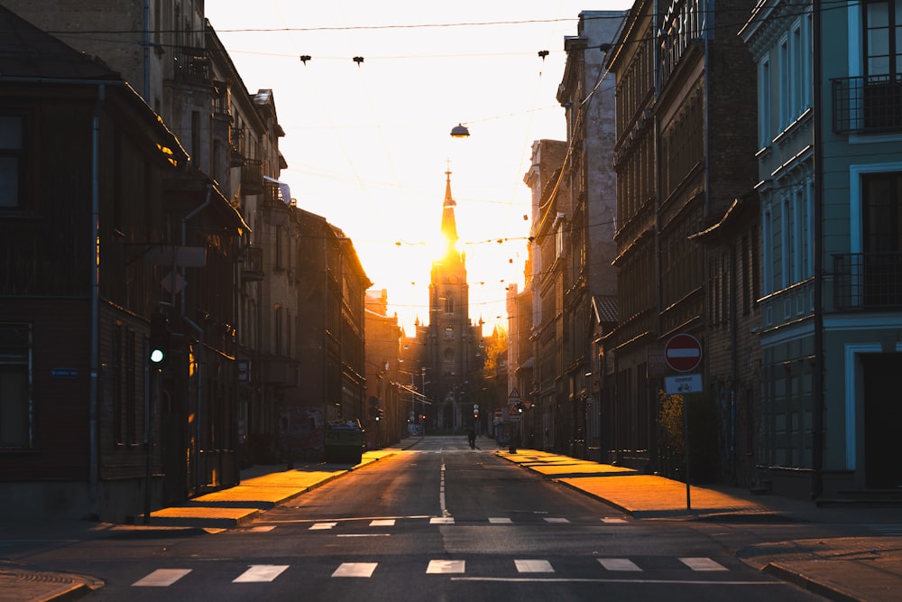 a city street at sunset with buildings on both sides