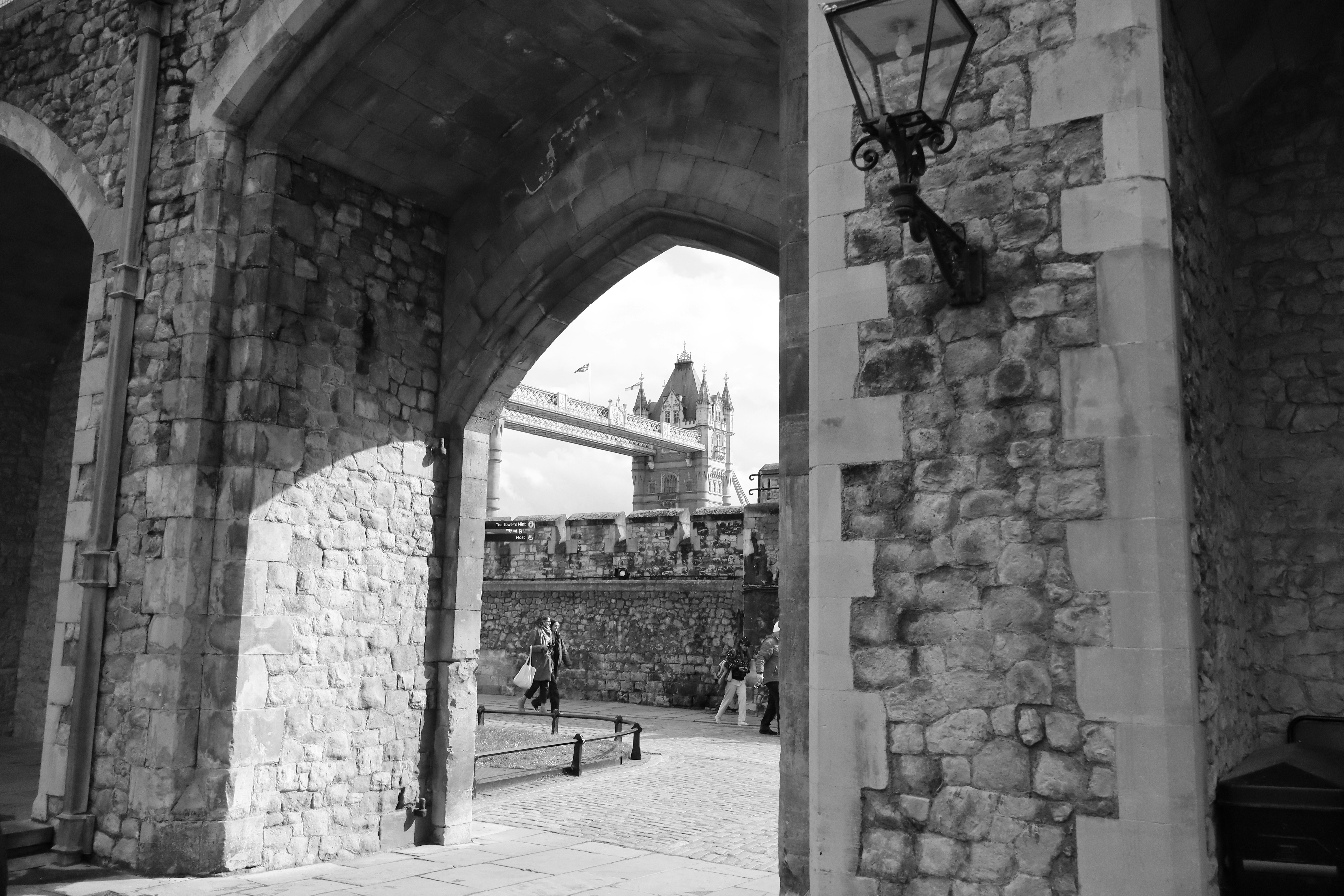 a black and white photo of people walking under a bridge