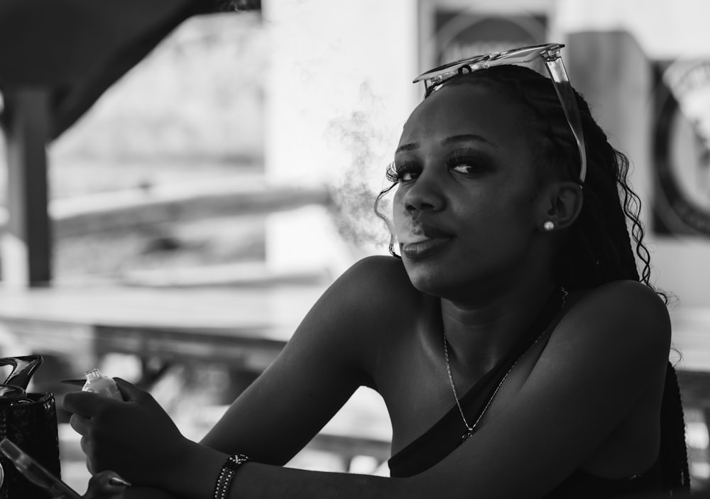 a woman sitting at a table smoking a cigarette