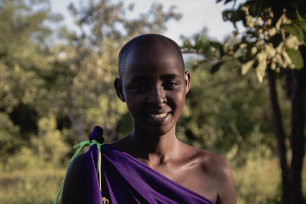 a woman in a purple dress smiles at the camera