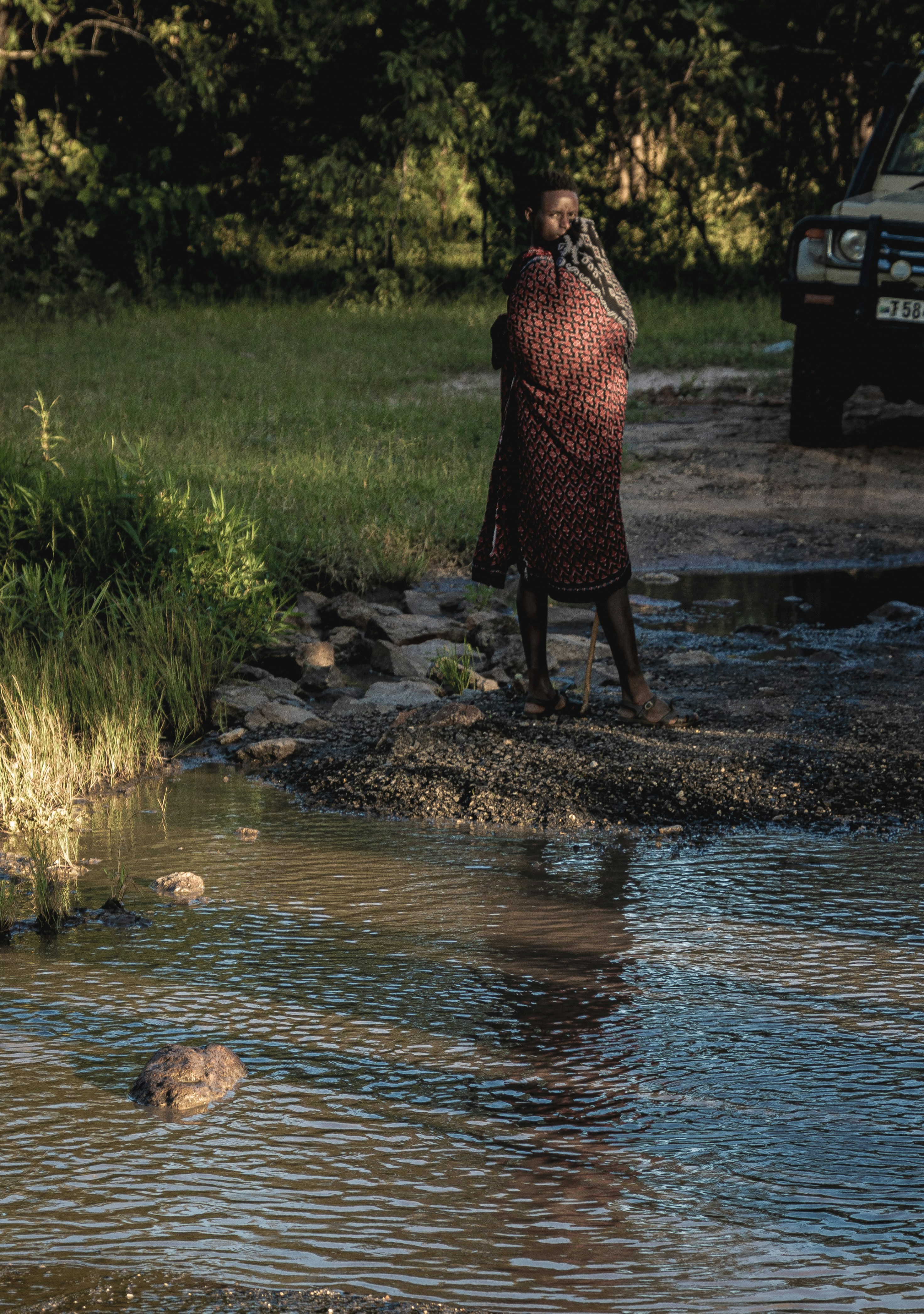 a woman in a red dress standing next to a body of water
