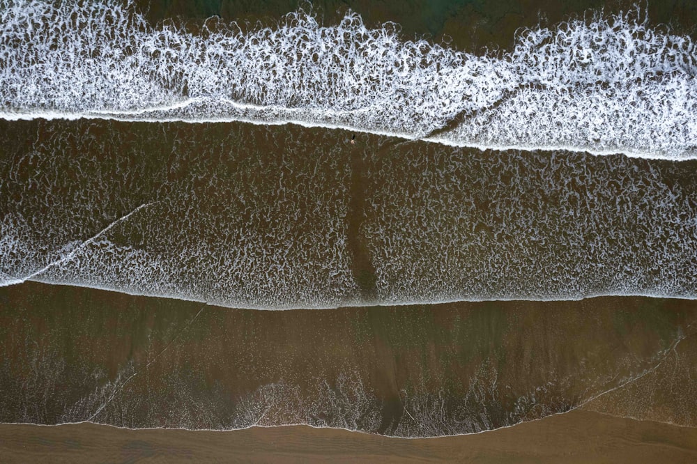 an aerial view of a beach with waves coming in