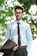 a man wearing glasses and a tie standing in front of a tree