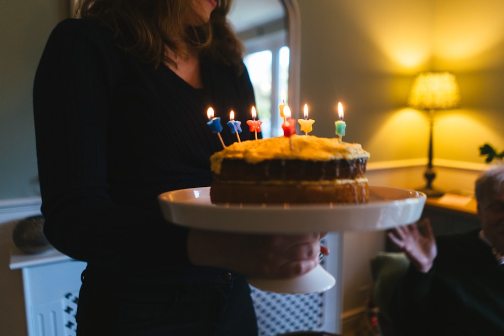 a woman holding a cake with lit candles on it
