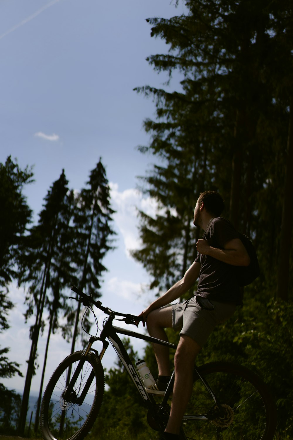 a man sitting on top of a bike next to a forest