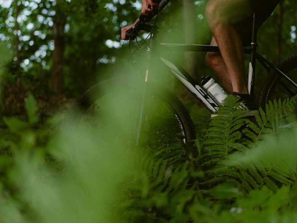 a man riding a bike through a lush green forest