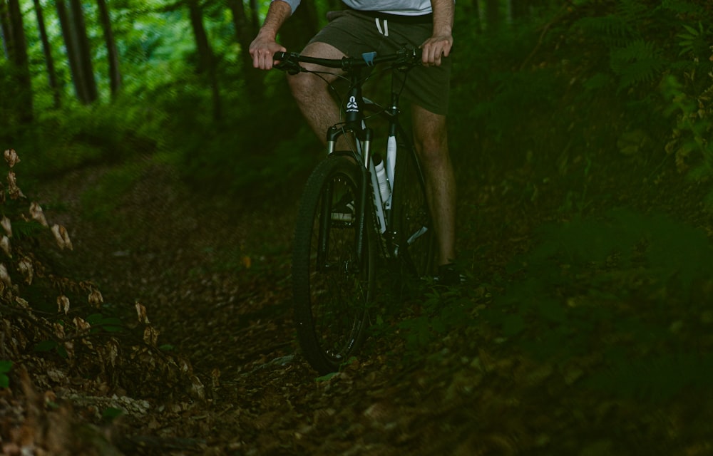 a man riding a bike through a lush green forest