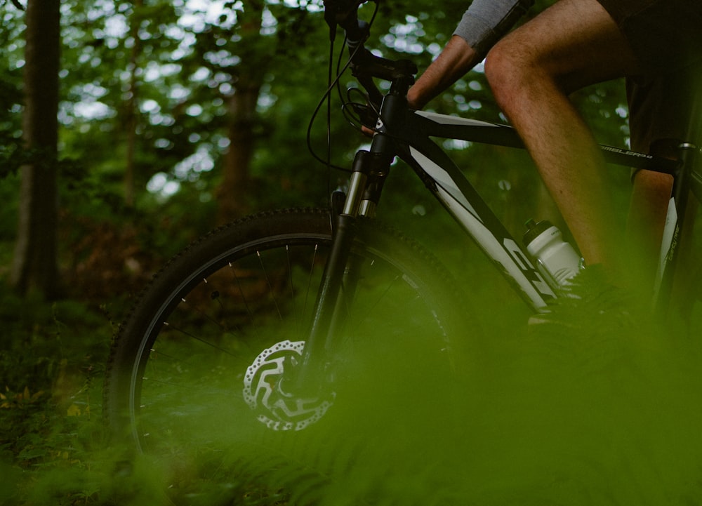 a man riding a bike through a lush green forest