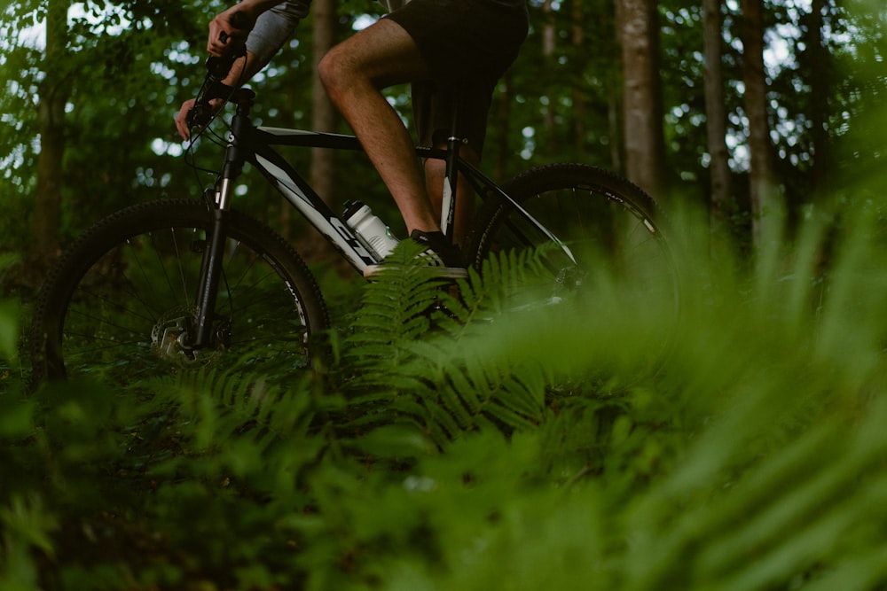 a man riding a bike through a lush green forest