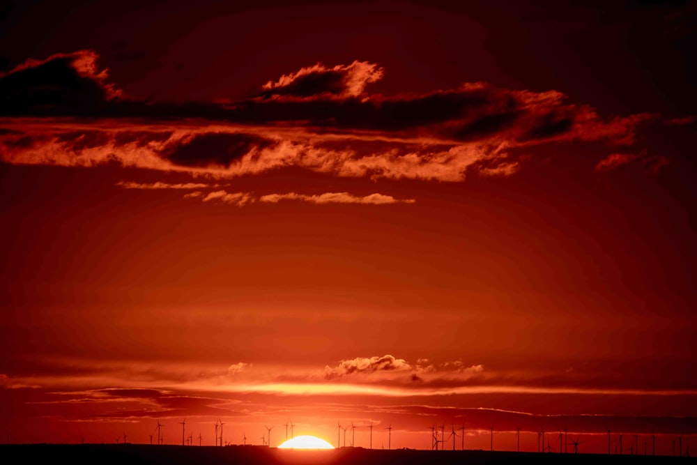 the sun is setting over a field of windmills