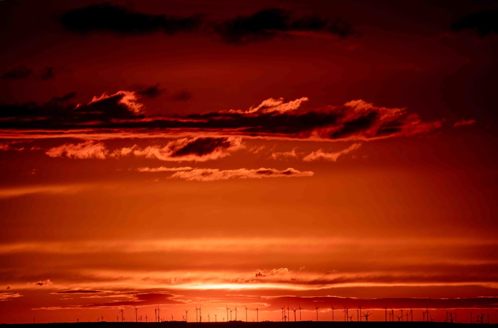un cielo rojo con una línea de molinos de viento en la distancia