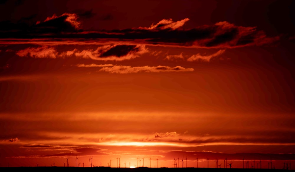 the sun is setting over a field of windmills