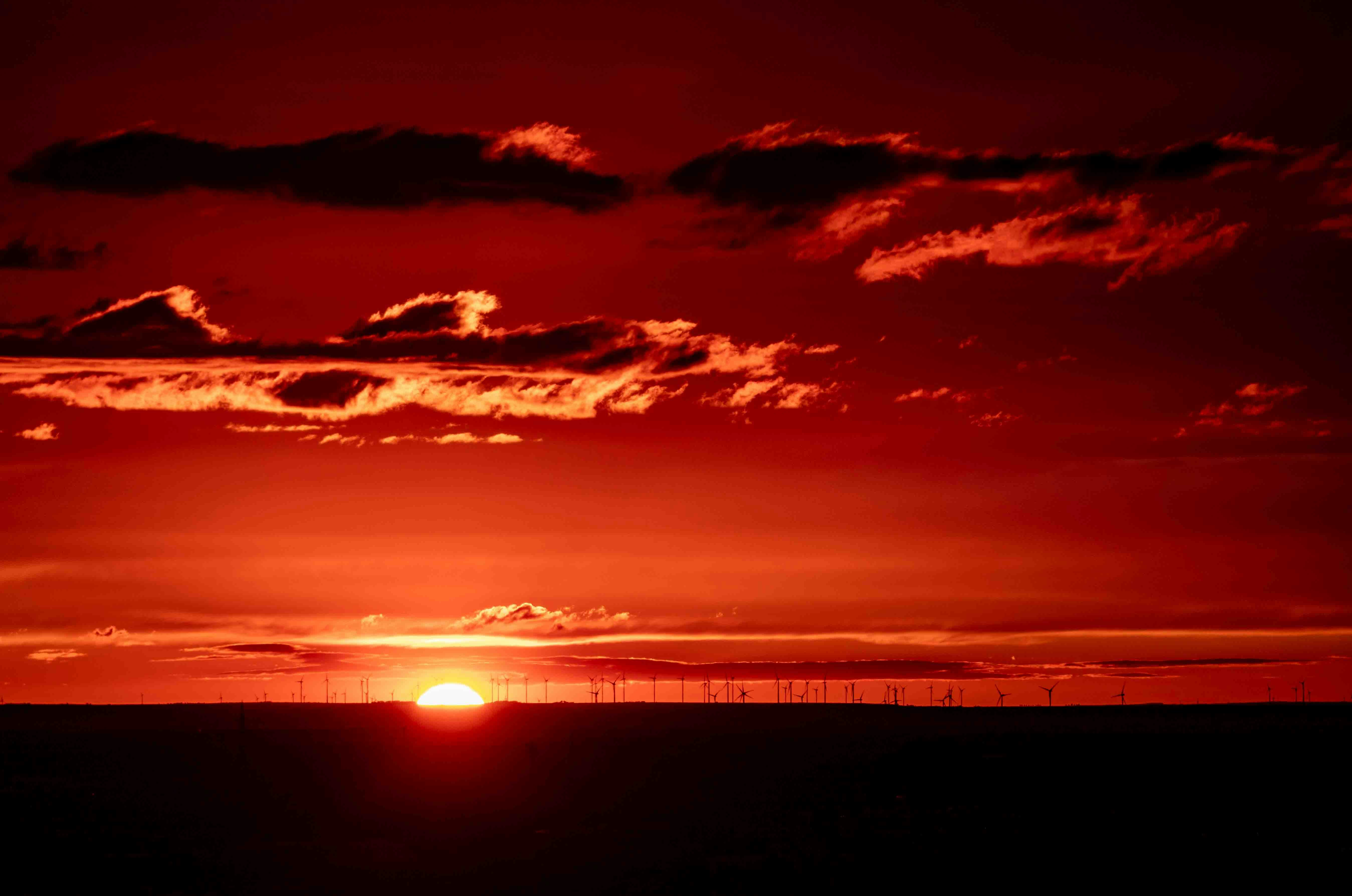 the sun is setting over the horizon of a field