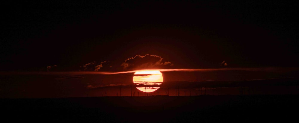 太陽は暗い空の地平線に沈んでいます