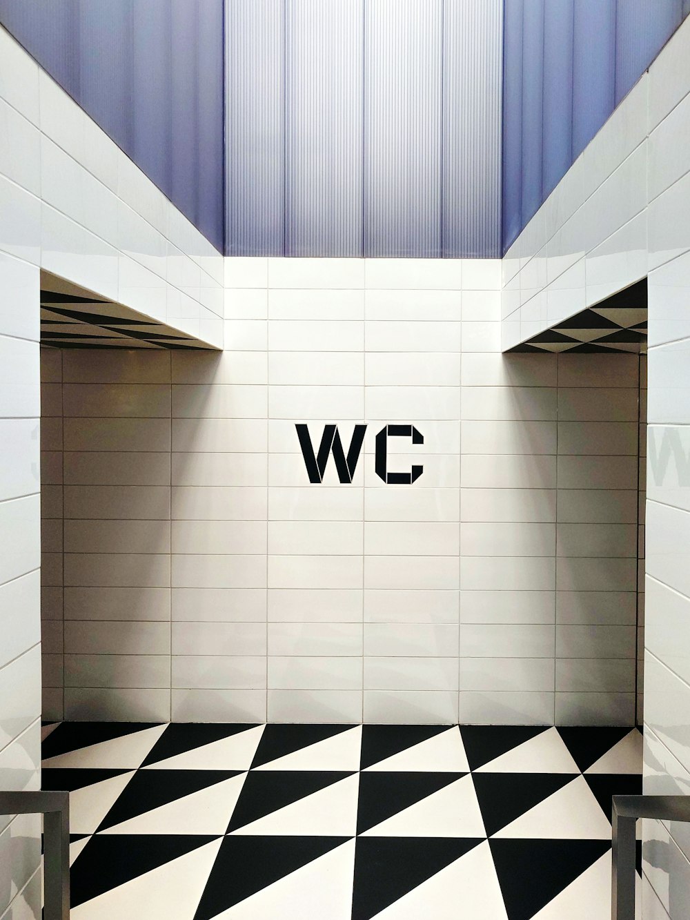 a black and white tiled bathroom with the word w c on the wall
