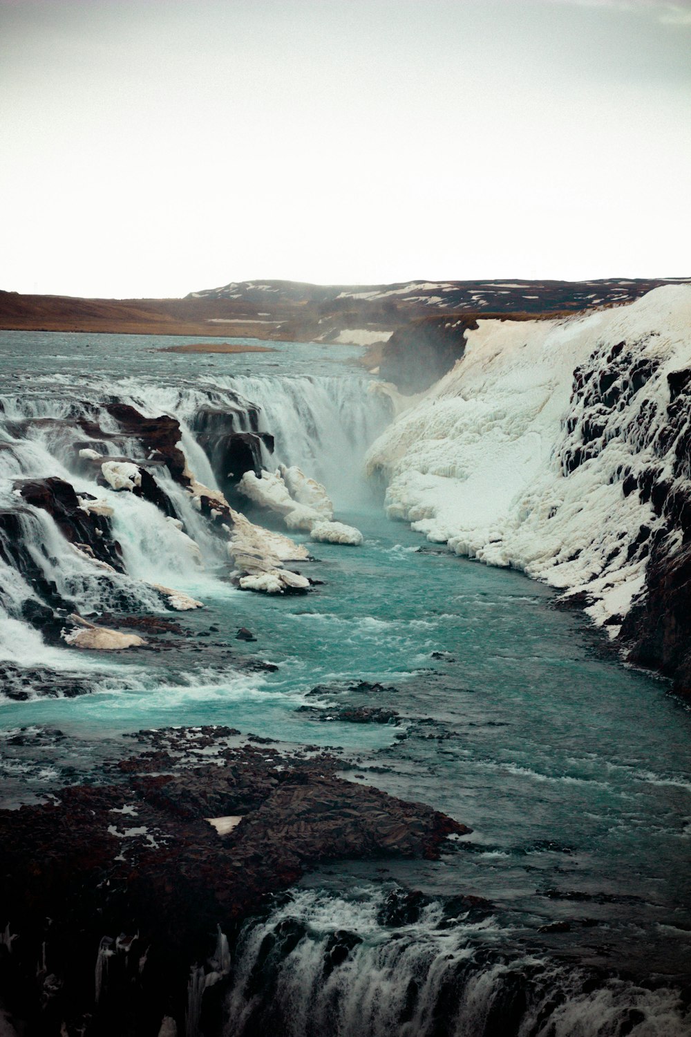 a river running through a canyon next to snow covered mountains