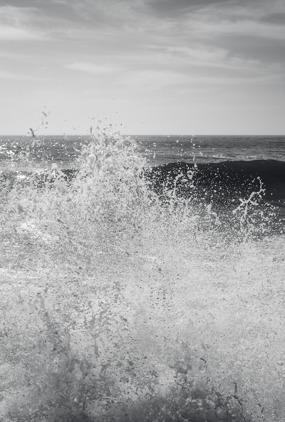 a black and white photo of a wave crashing