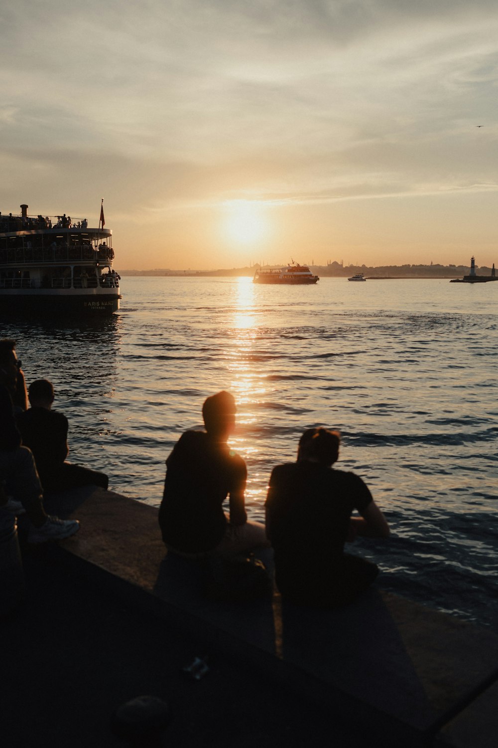 a group of people sitting on a dock watching the sun go down