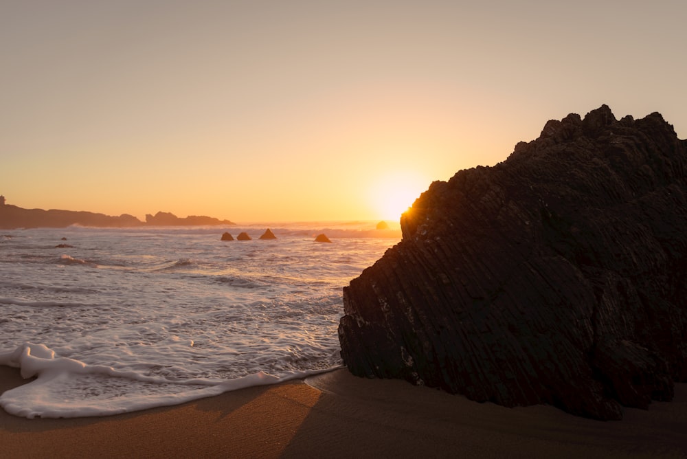 the sun is setting over the ocean on the beach