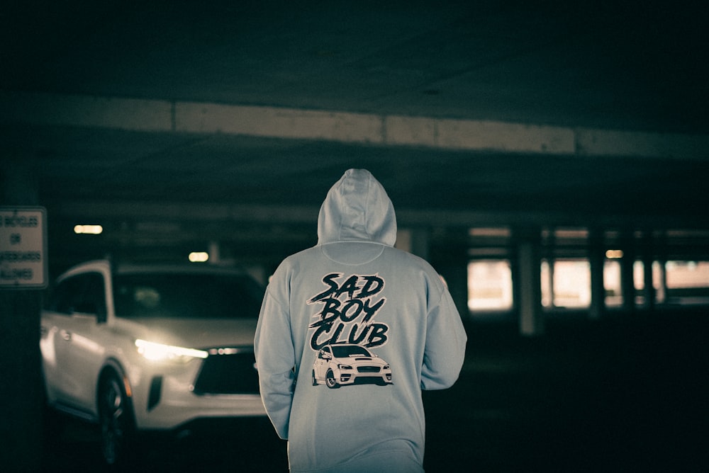 a person in a hoodie standing in a parking garage