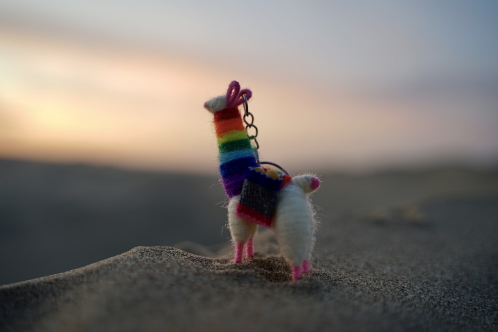 a small toy llama with a rainbow sweater on it's back