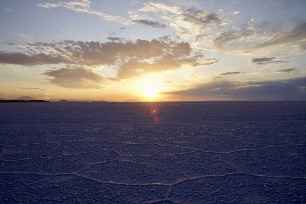 the sun is setting over a vast expanse of snow