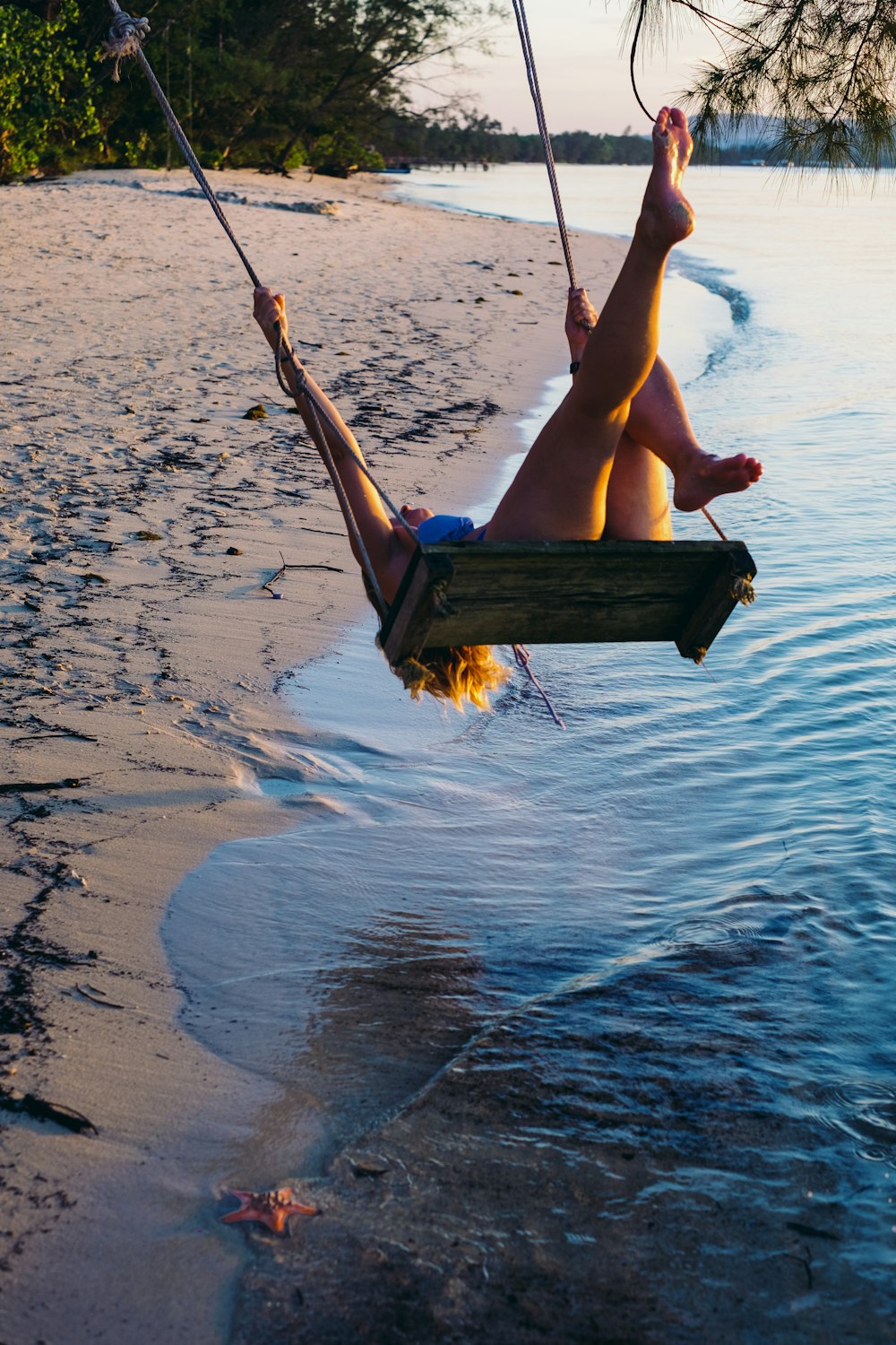 a woman sitting in a hammock on the beach