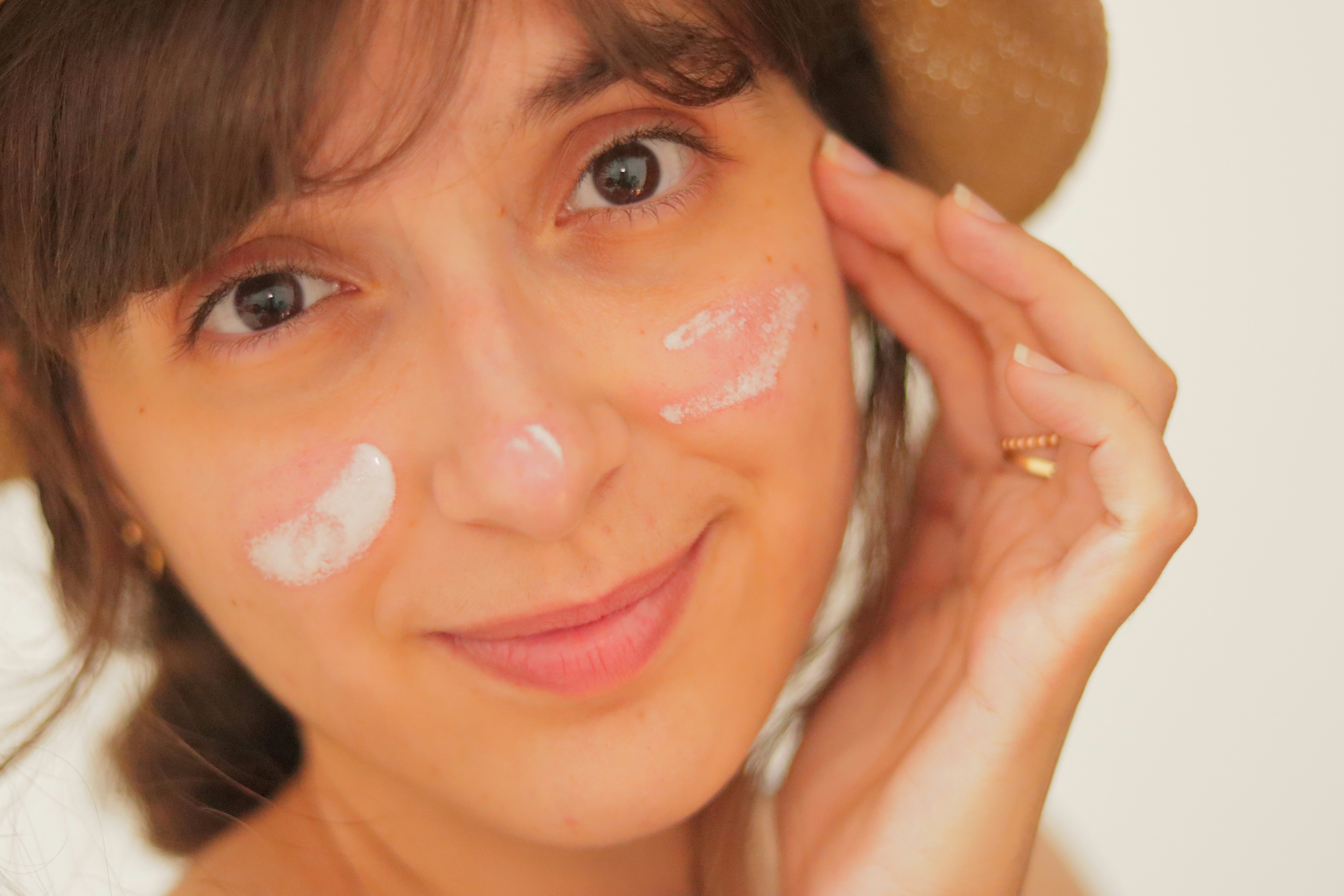 Black woman applying sunscreen to her face outdoors in bright sunlight