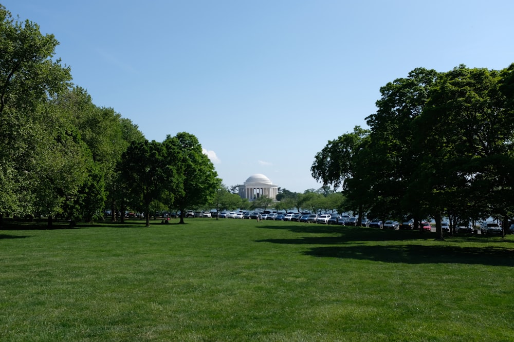 a large grassy field with trees and a building in the background