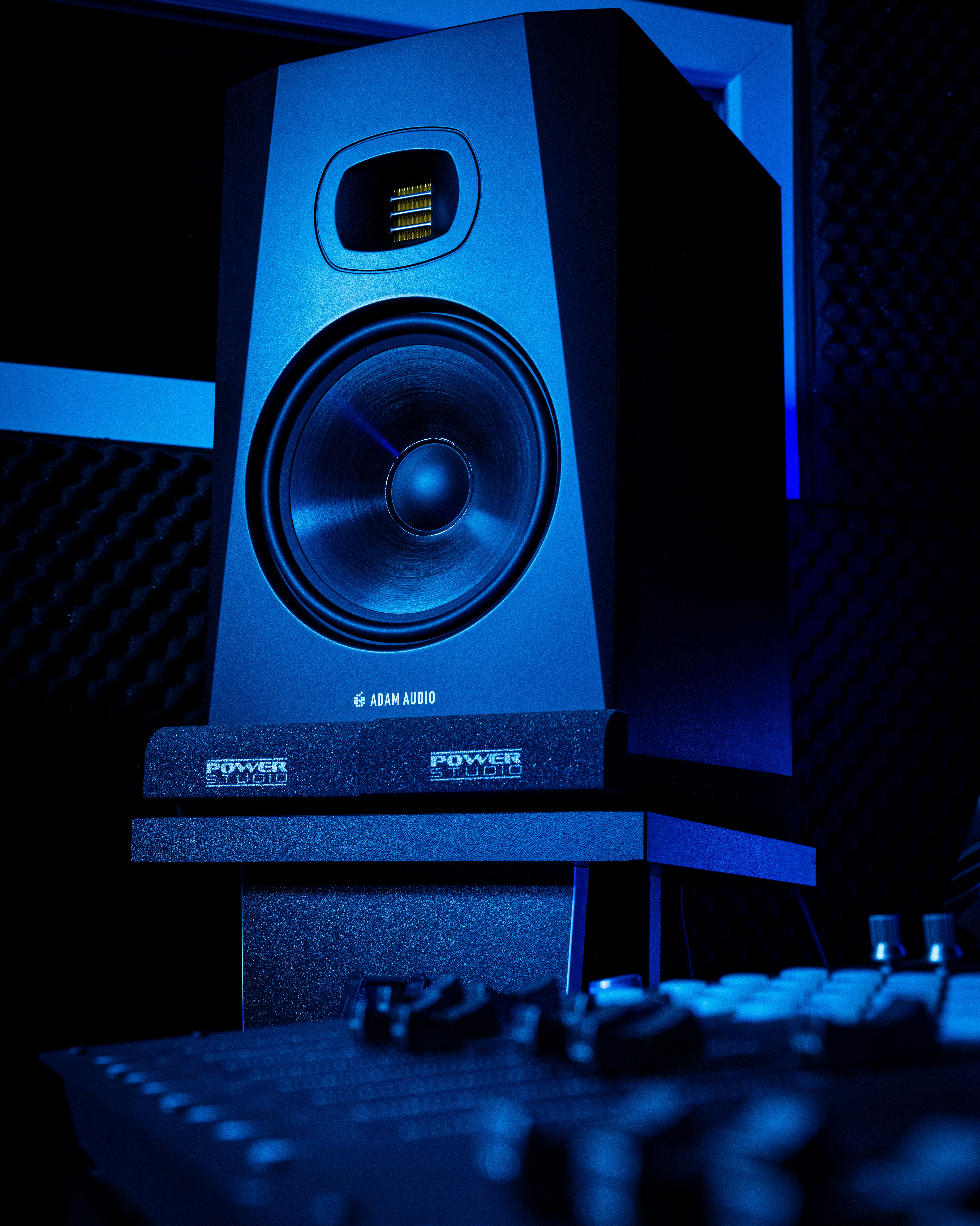 Dark studio speaker and soundboard with dramatic side lighting, deep blacks