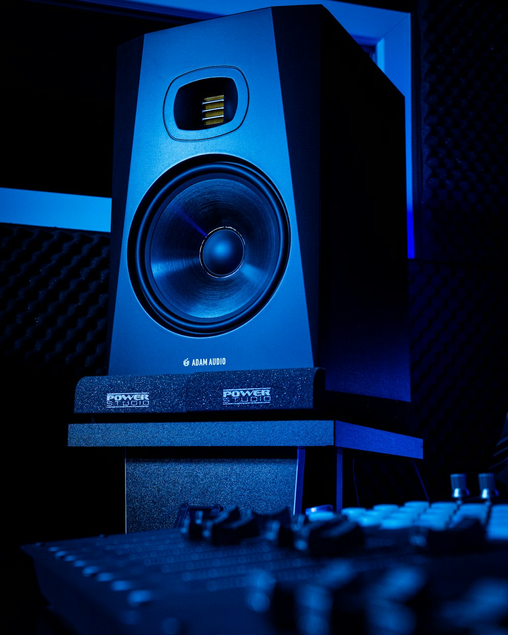 a large speaker sitting on top of a desk next to a keyboard