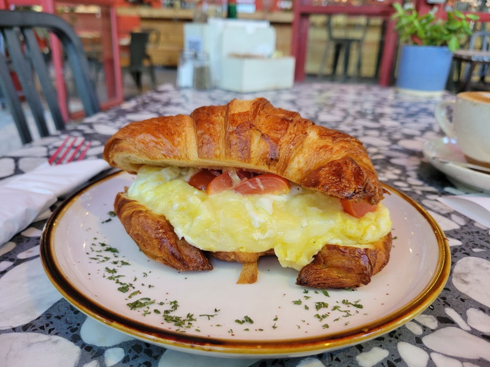 a croissant sandwich on a plate on a table