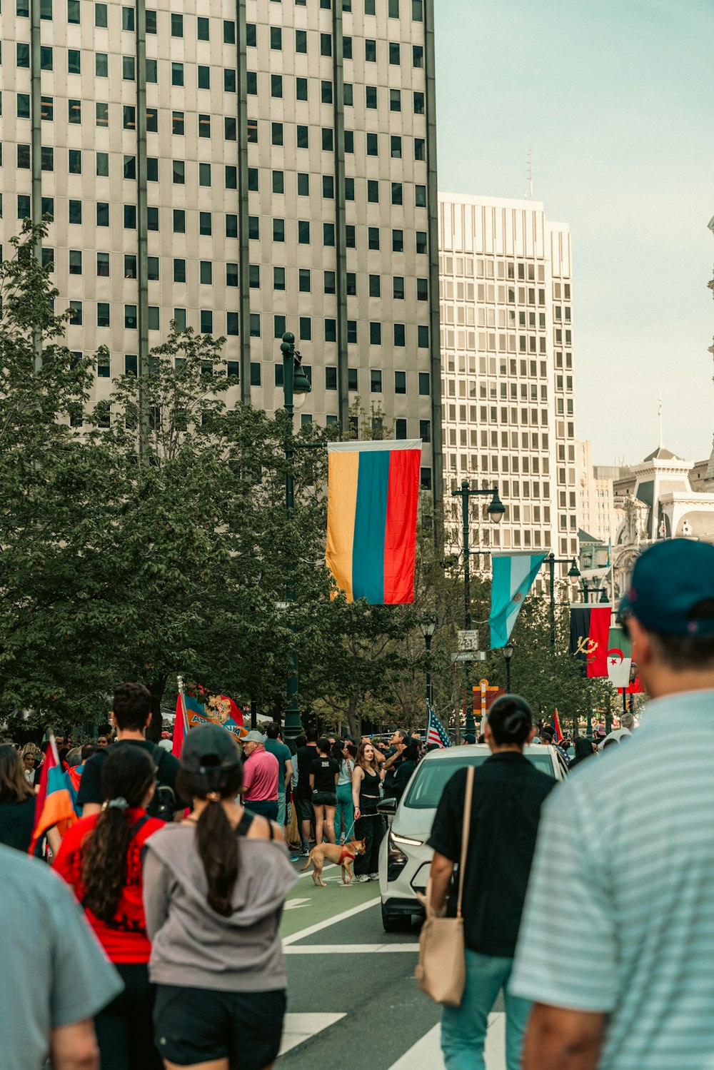 a crowd of people walking down a street next to tall buildings