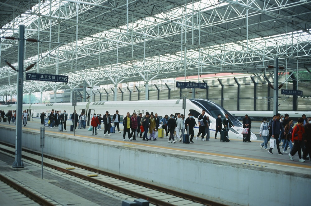 a group of people standing on a platform next to a train