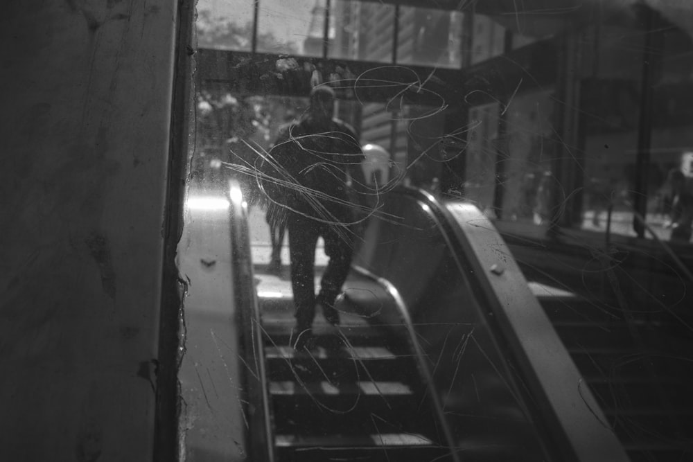 uma foto em preto e branco de uma pessoa em uma escada rolante